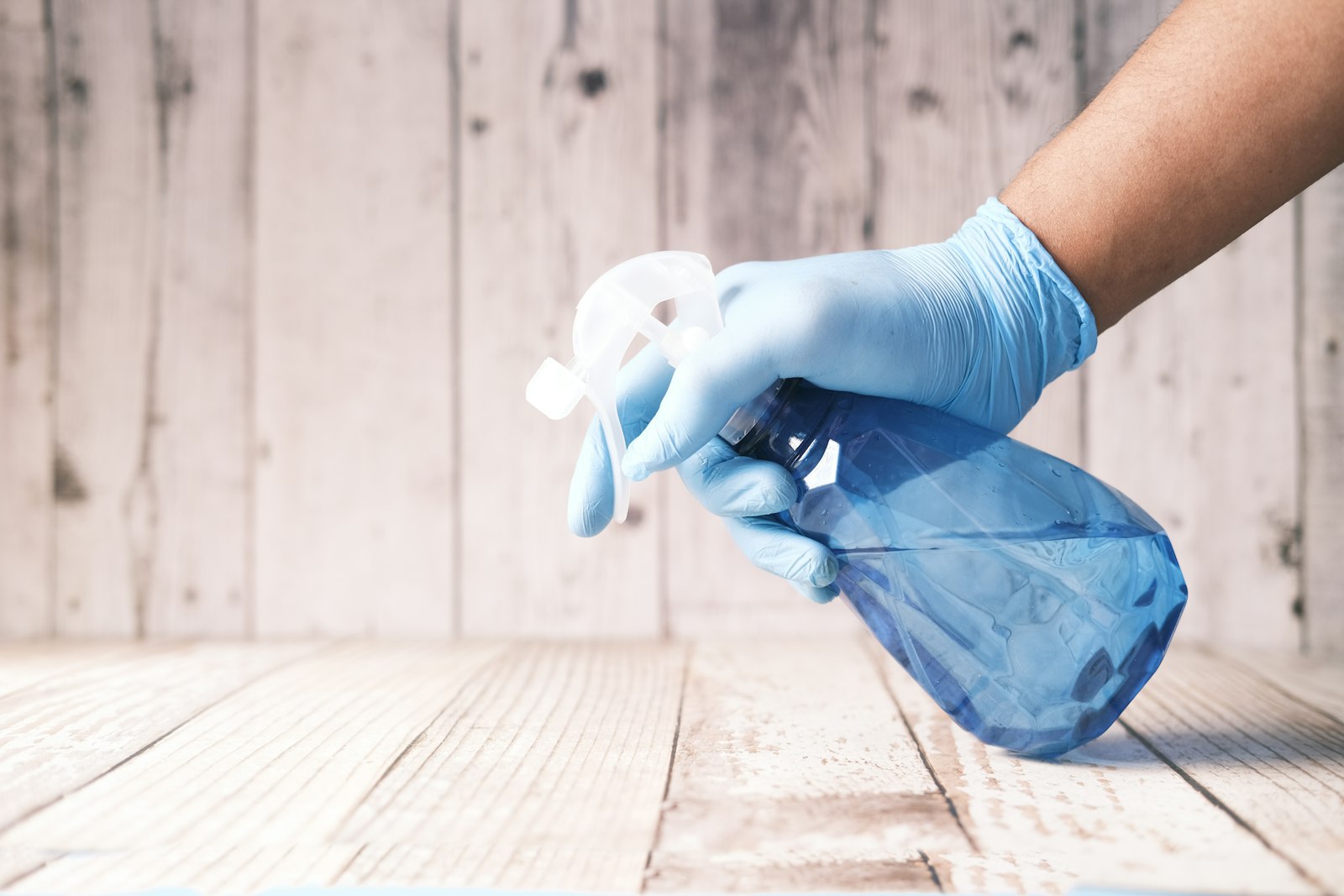 Gloved hand holding a spray bottle